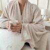 Zbliżenie na dzianinowy kocyk w jasnym beżu, pokazując miękką fakturę tkaniny premium, wytrzymały splot i przyjemny w dotyku materiał