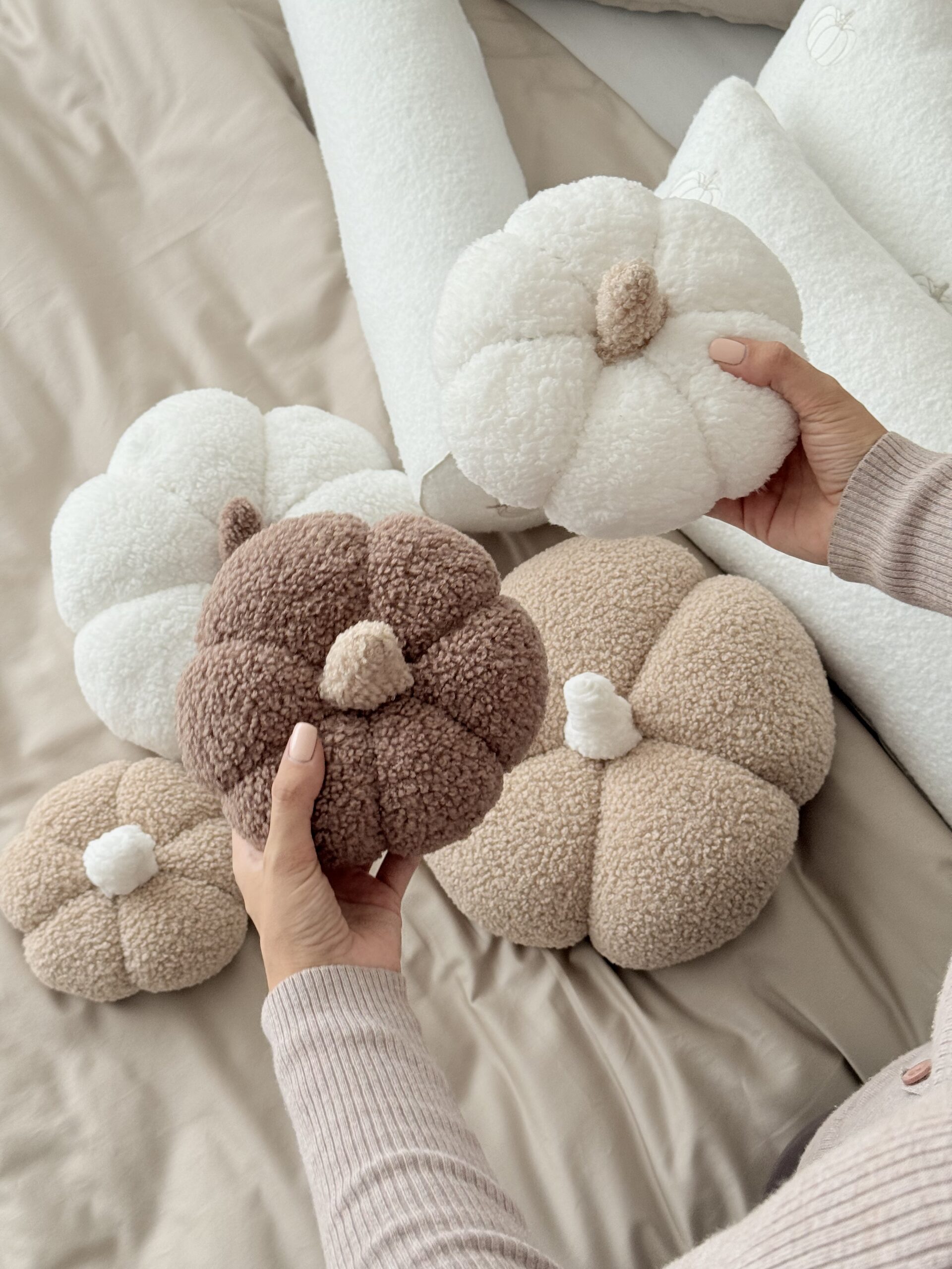 Ręcznie robiona poduszka dynia z miękkiego materiału boucle, z wypełnieniem, trzymana w dłoniach - produkt Simonila z jesiennej kolekcji